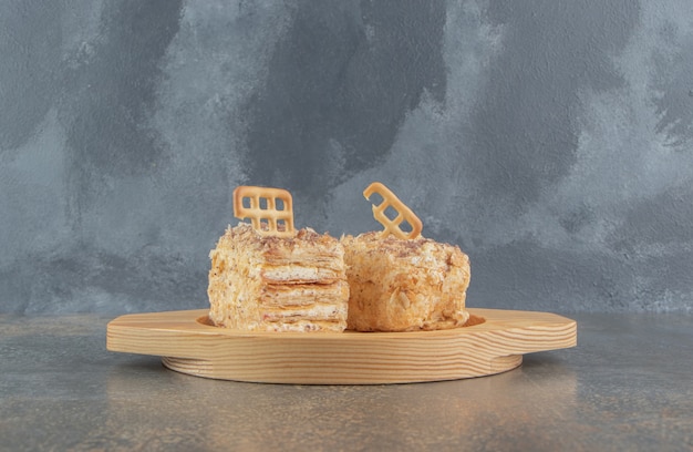 Guarnizione di biscotto sulle fette di torta su un piatto di legno