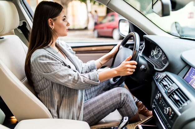 Guidare in città. Giovane donna attraente sorridente e guardando dritto mentre si guida un'auto