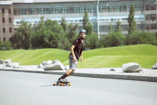 Guidatore di skateboard facendo un trucco in strada nella giornata di sole