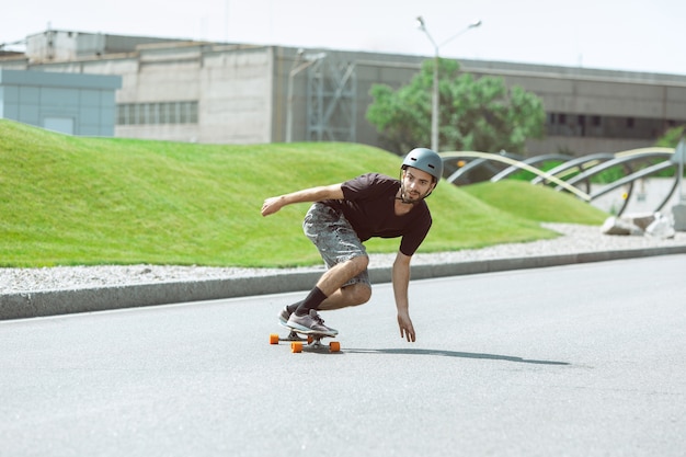 Guidatore di skateboard facendo un trucco in strada nella giornata di sole