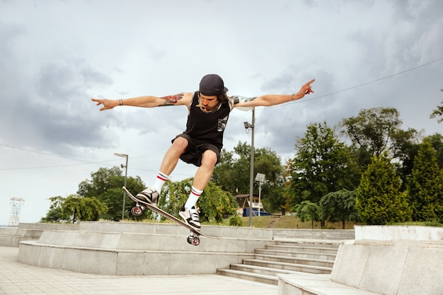 Guidatore di skateboard facendo un trucco per la strada della città in una giornata nuvolosa