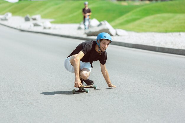 Guidatore di skateboard facendo un trucco sulla strada della città in una giornata di sole.