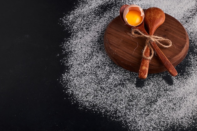 Guscio d'uovo con tuorlo in un cucchiaio di legno sul piatto di legno.