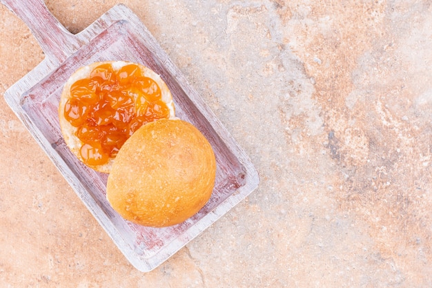 Gustosa marmellata con panino su una tavola, sullo sfondo di marmo.