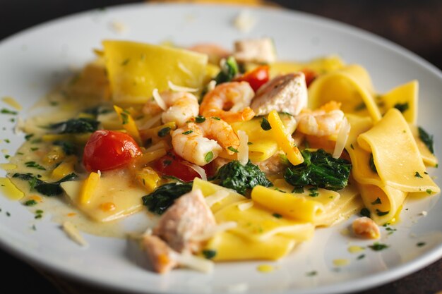 Gustosa pasta appetitosa con gamberi, verdure e spinaci servita sul piatto.