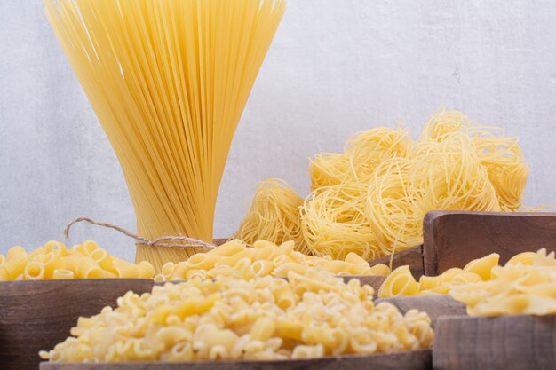 Gustosa pasta cruda e maccheroni su ciotole di legno.