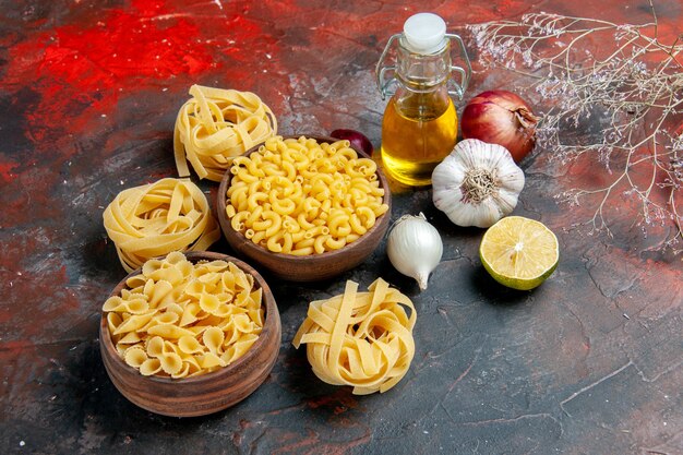 Gustosa preparazione per la cena con pasta cruda in varie forme e bottiglia di olio all'aglio limone all'aglio su sfondo di colore misto