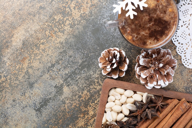 Gustosa tazza di cacao con bastoncini di cannella e pigne nelle quali su sfondo marmo. Foto di alta qualità