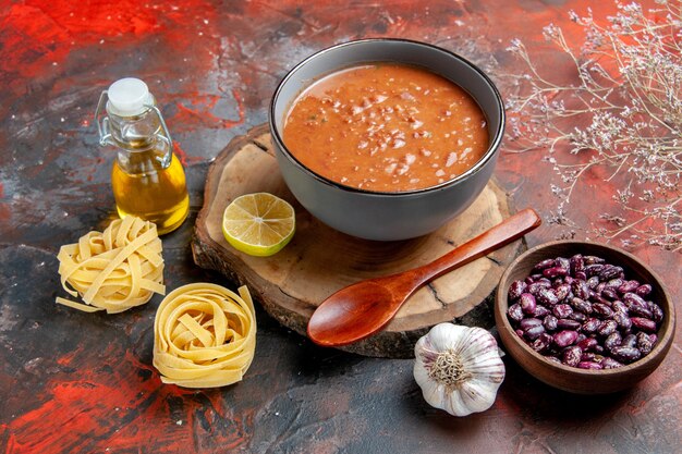 Gustosa zuppa per cena con un cucchiaio e limone su un vassoio di legno fagioli cipolla garica e altri prodotti sulla tabella di colori misti