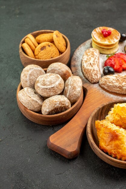 Gustose frittelle di vista frontale con diversi dolci sul dessert di zucchero torta superficie scura