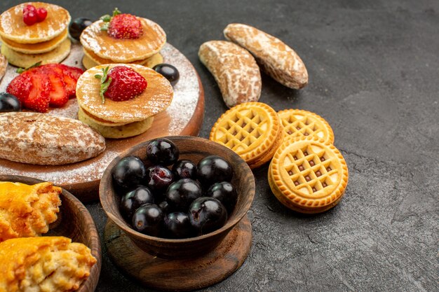 Gustose frittelle di vista frontale con diversi dolci sul dessert torta di zucchero scrivania scuro