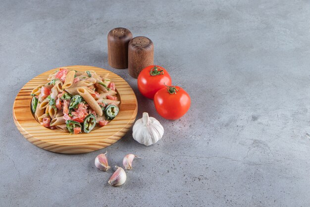 Gustose penne con verdure fresche tritate su piatto di legno.