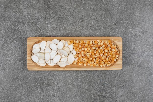 Gustosi semi di zucca e chicchi di mais sul piatto di legno.