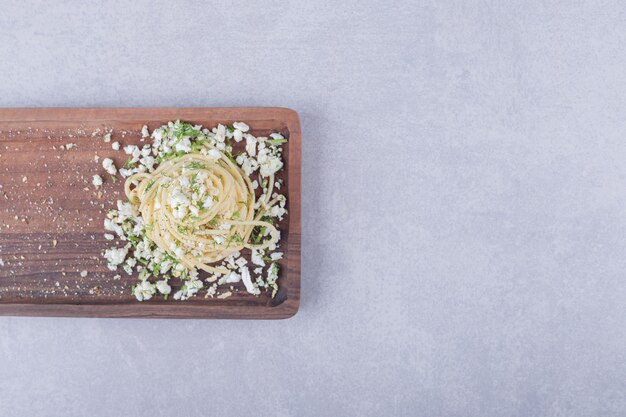 Gustosi spaghetti bolliti con formaggio grattugiato su tavola di legno.