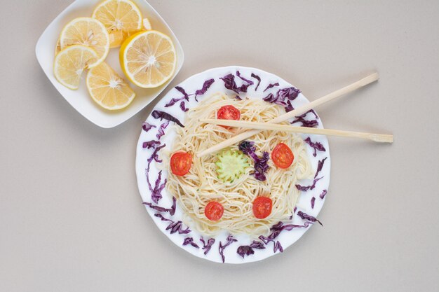 Gustosi spaghetti e fette di limone sulla superficie bianca