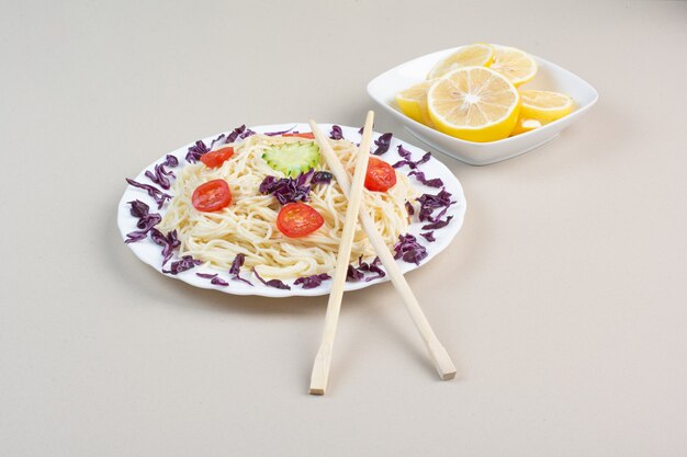 Gustosi spaghetti e fette di limone sulla superficie bianca