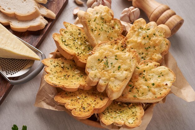 Gustoso pane fatto in casa con aglio, formaggio ed erbe aromatiche sul tavolo della cucina.
