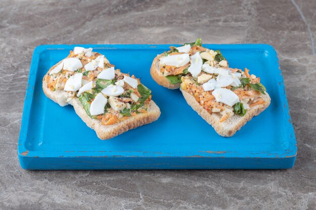 Gustoso pane tostato con verdure a fette sul piatto blu.