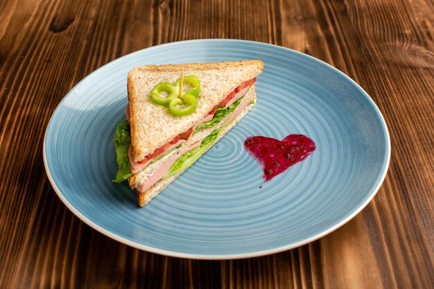 gustoso panino con insalata di pomodori verdi all'interno del piatto blu su fondo marrone