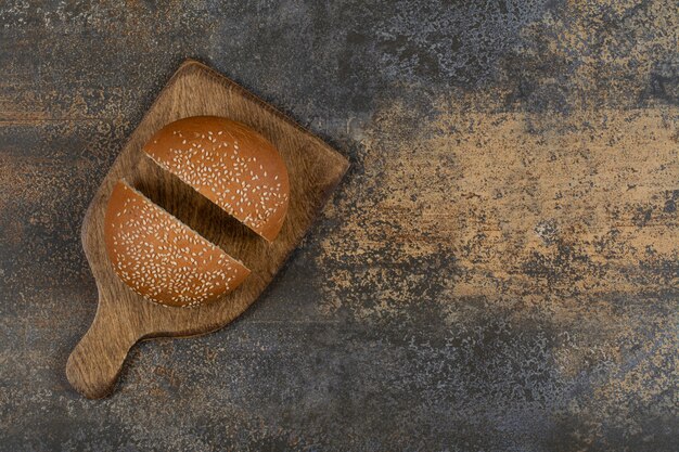 Gustoso panino mezzo tagliato con semi di sesamo su tavola di legno.