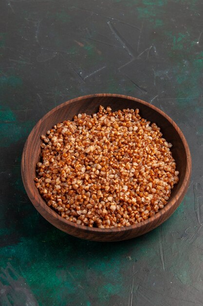 Gustoso pasto di grano saraceno cucinato a metà vista all'interno del piatto marrone sulla superficie verde scuro