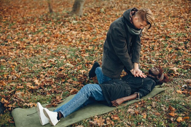 Guy aiuta una donna. La ragazza africana sta mentendo inconscia. Fornire il primo soccorso nel parco.