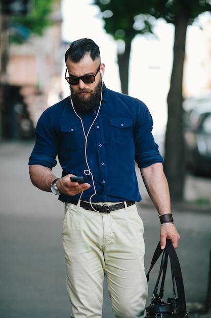 Guy camminare mentre usando il suo cellulare