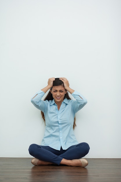 Ha sottolineato la donna seduta sul pavimento e Clutching Capo