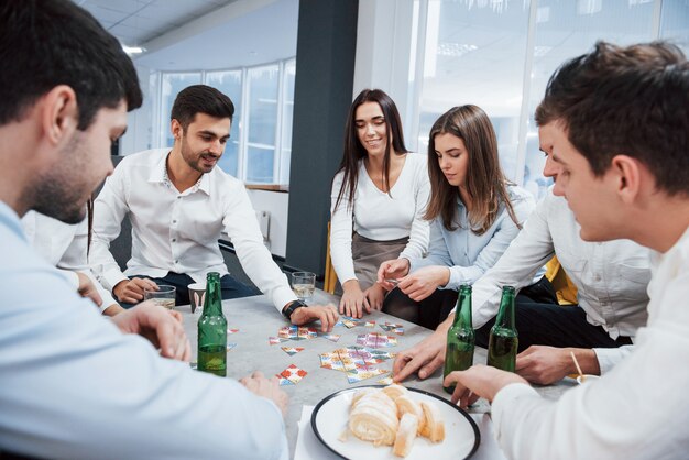 Hai bisogno di un po 'più di concentrazione. Rilassarsi con il gioco. Festeggiamo un affare di successo. Giovani impiegati seduti vicino al tavolo con l'alcol