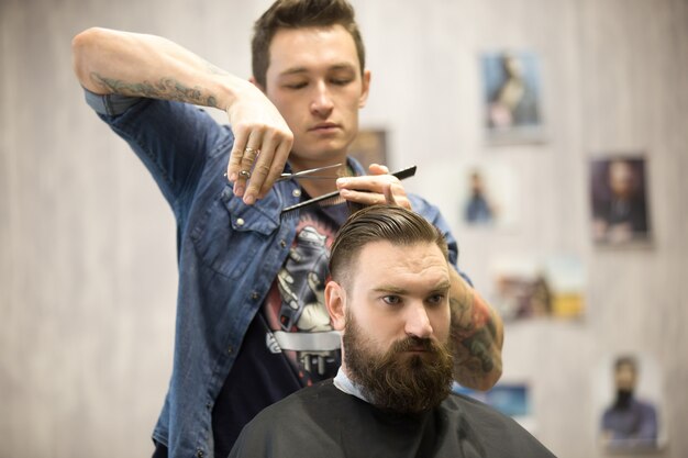 Hairstylist che fa un taglio di capelli per il cliente maschio