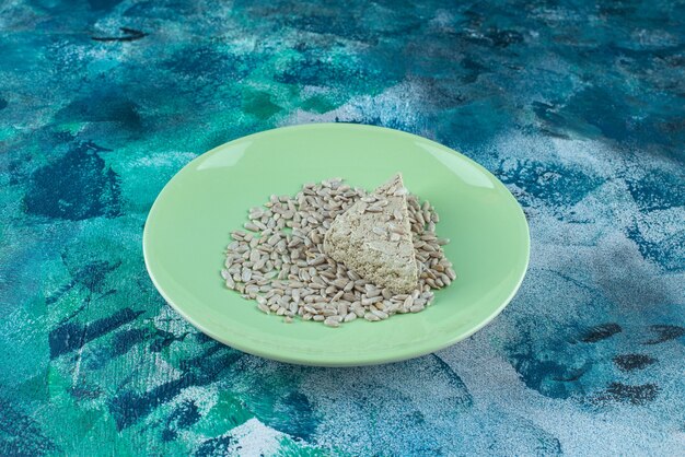 Halva di girasole affettato con semi sul piatto, sul tavolo di marmo.