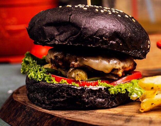 Hamburger al formaggio di manzo in padella al cioccolato nero con verdure e fast food.