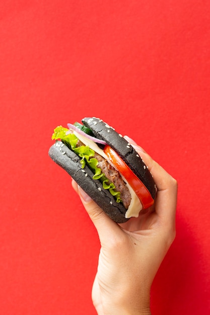 Hamburger con panino nero su sfondo rosso