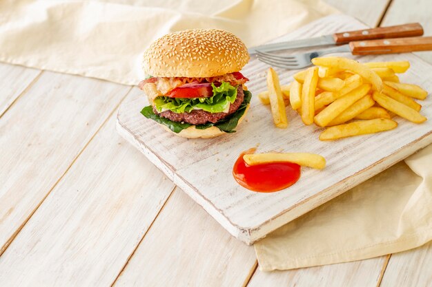 Hamburger con patatine fritte e salsa su tavola di legno