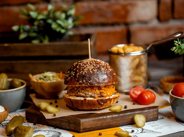 Hamburger con tortino di erbe di pollo servito con patatine fritte, insalata di cavolo e sottaceti