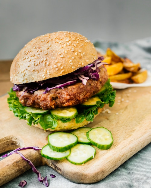 Hamburger del primo piano dell&#39;angolo alto con le fritture sul bordo di legno