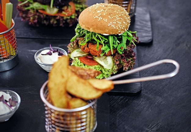 Hamburger delizioso, patatine fritte con insalata su un tavolo.