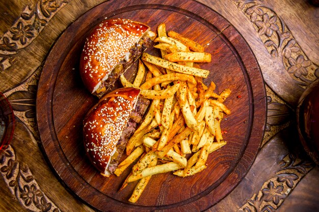 Hamburger della carne sulla vista superiore delle patate fritte del bordo di legno