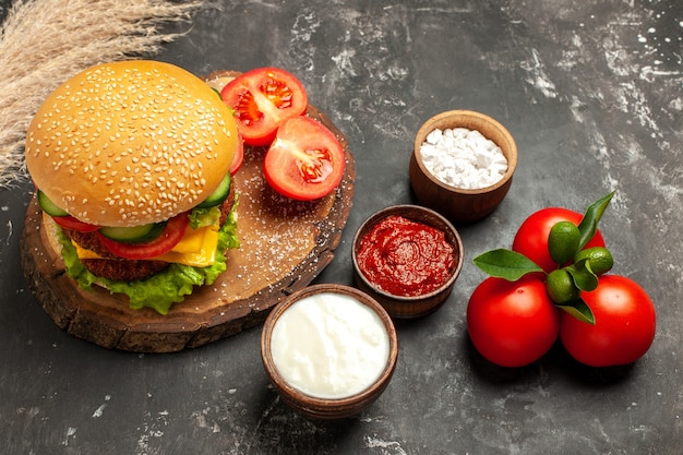 Hamburger di carne di formaggio con vista a mezza altezza con condimenti su panino con patatine fritte di superficie scura