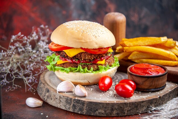 Hamburger di carne gustoso vista frontale con patatine fritte sulla scrivania scura