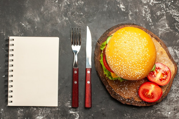 Hamburger di carne vista dall'alto con verdure e formaggio sul panino fast-food panino scuro della scrivania