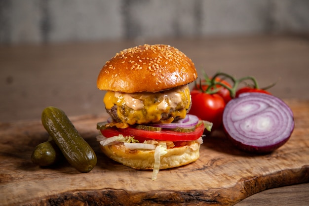 Hamburger di carne vista frontale con cipolle sottaceti e pomodori sullo scrittorio di legno