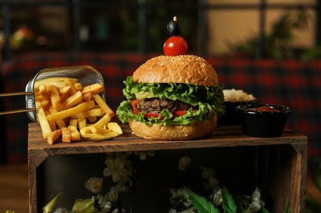 Hamburger di carne vista frontale con patatine fritte ketchup e maionese su un supporto