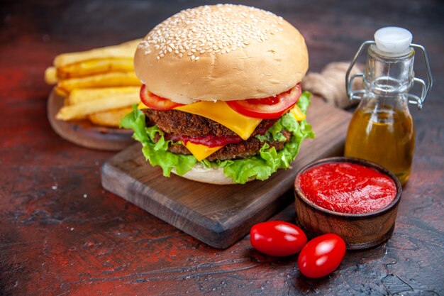 Hamburger di carne vista frontale con patatine fritte su sfondo scuro