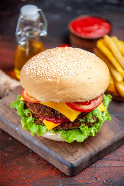 Hamburger di carne vista frontale con pomodoro, formaggio e insalata su sfondo scuro