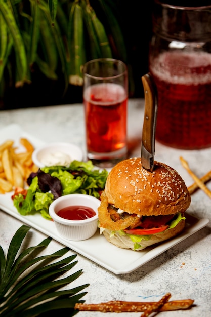 Hamburger di manzo con anelli di cipolla Insalata di pomodori servita con insalata e patatine fritte