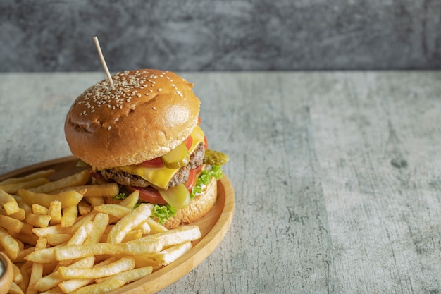 Hamburger e patate fritte in un piatto di legno