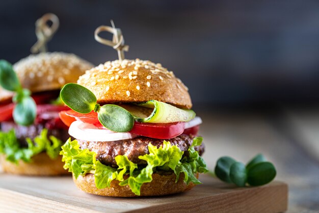 Hamburger fatti in casa con cotoletta, lattuga fresca, pomodori, cipolle su un tavolo di legno. copia spazio
