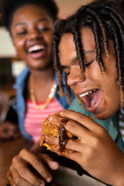 Hamburger mangiatore di uomini di vista laterale in un modo divertente