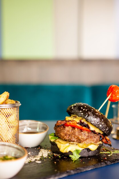 Hamburger nero con carne di manzo e patatine fritte. Gustoso appetitoso